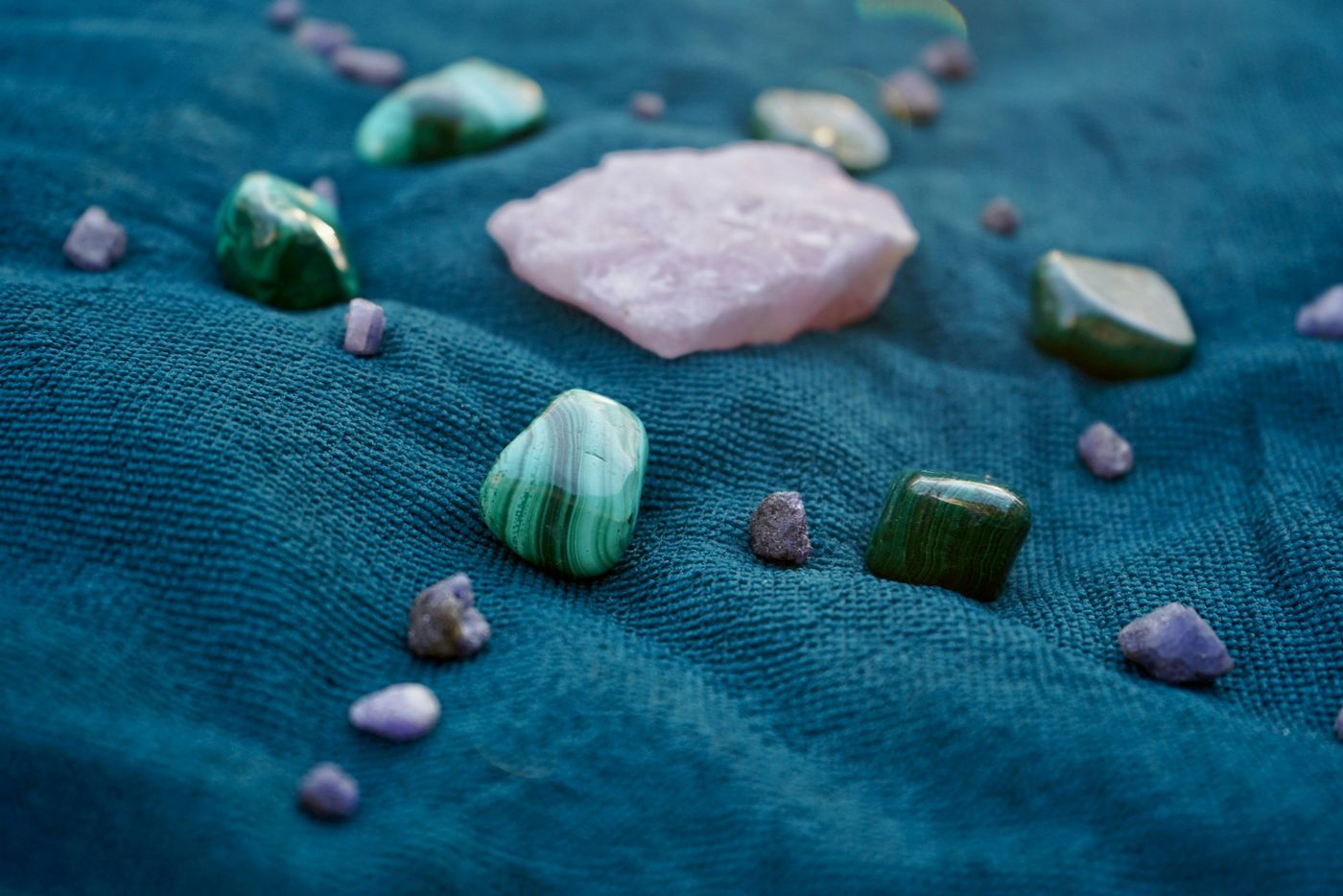 Rose quartz and green tumbled stones arranged on a blue cloth